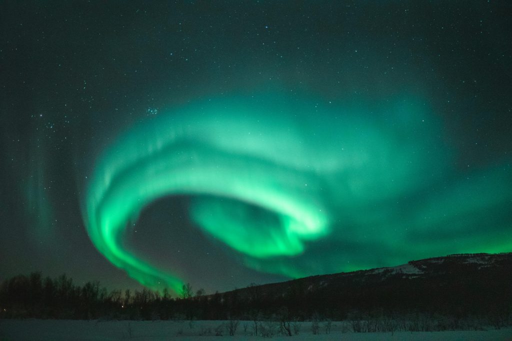 Captivating view of the Northern Lights dancing above a snowy landscape under a starry night sky.